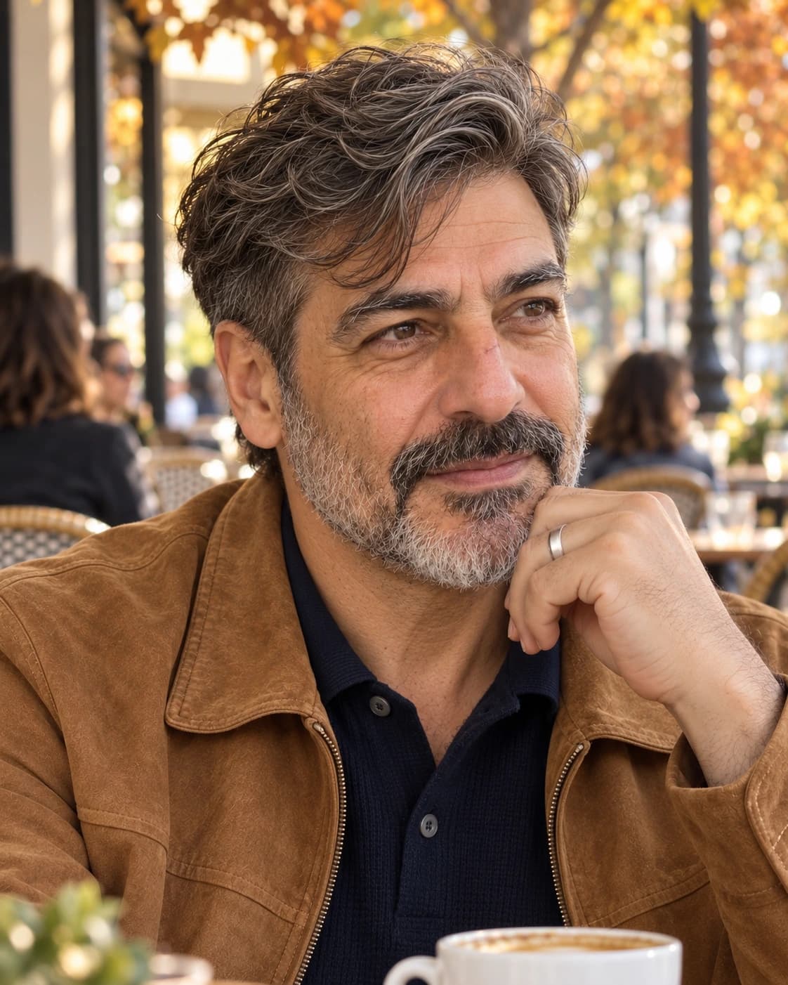 Man in his 50s with four inches of loose wavy hair on top swept to a side part over #2 sides, three-quarter view on a café terrace in autumn