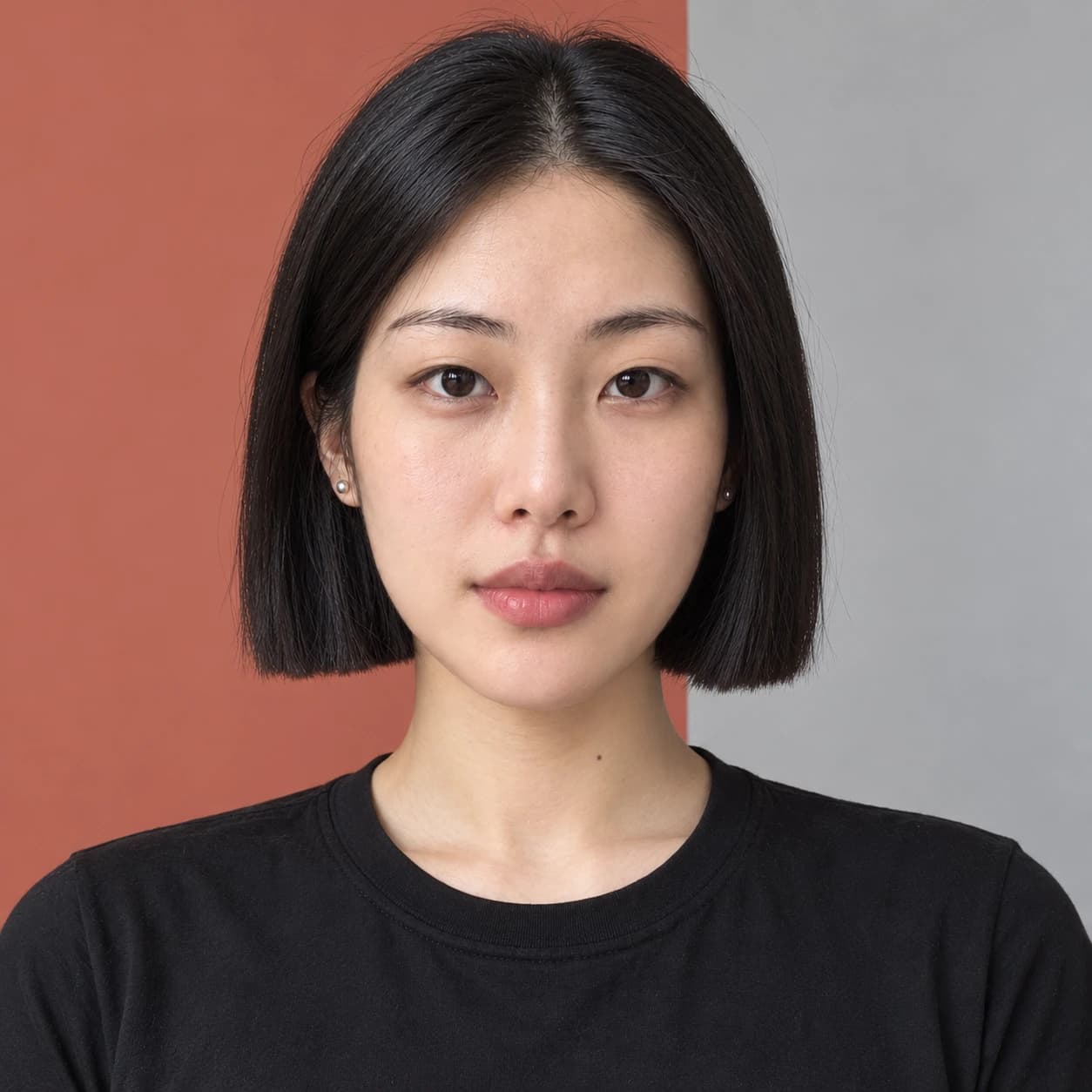 Woman in her mid-20s with a glossy one-length chin bob and center part, straight-on view against a minimal graphic studio backdrop